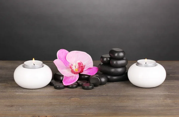 난초 꽃과 회색 배경에 나무 테이블에 촛불 스파 돌 — 스톡 사진