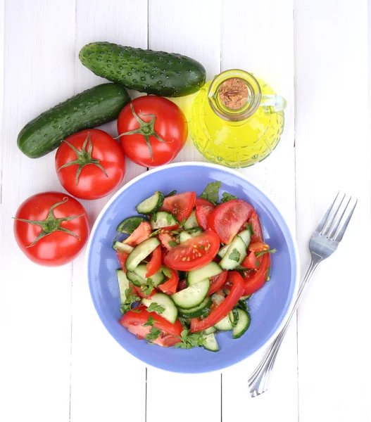 Verse salade met tomaten en komkommers op witte houten achtergrond — Stockfoto