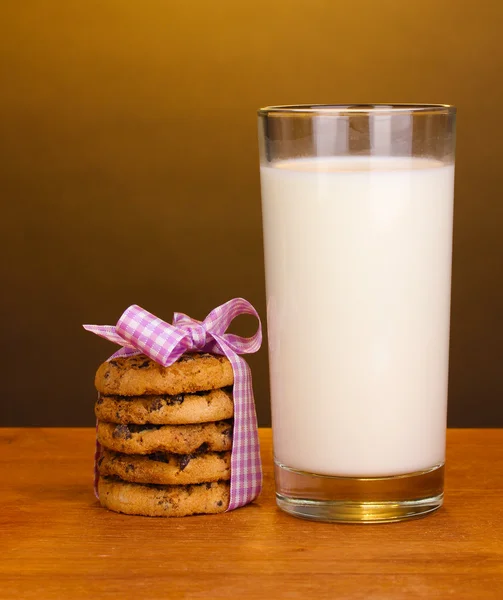 Bicchiere di latte e biscotti su tavolo di legno su sfondo marrone — Foto Stock