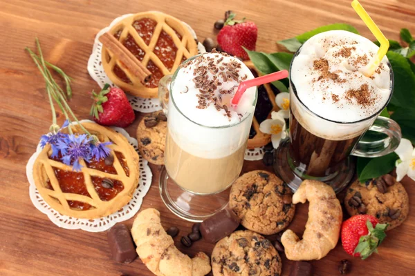 Copos de coquetel de café na mesa de madeira com doces e flores — Fotografia de Stock