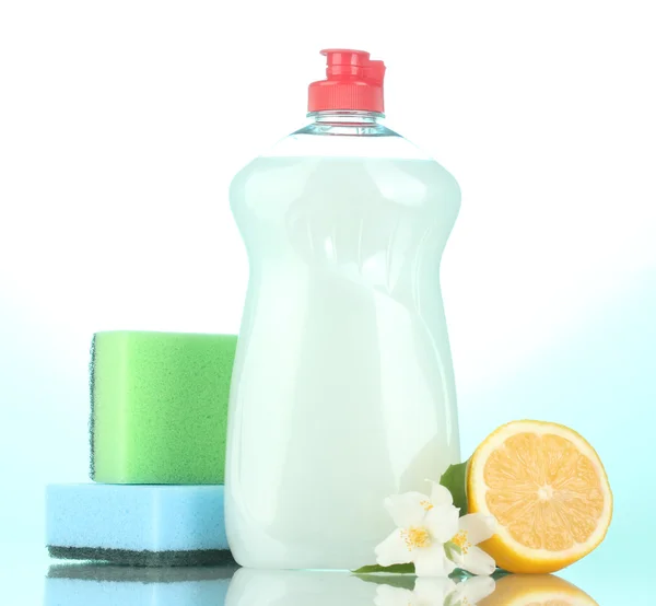 食器洗い液体スポンジと青色の背景色の花とレモン添え — ストック写真