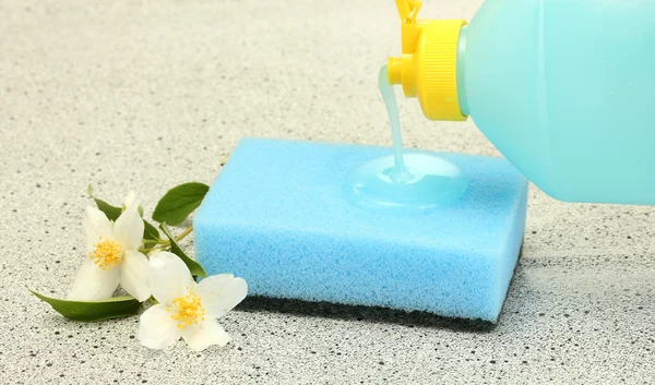Esponja brilhante e flor com líquido de lavagem de prato no fundo de mármore — Fotografia de Stock