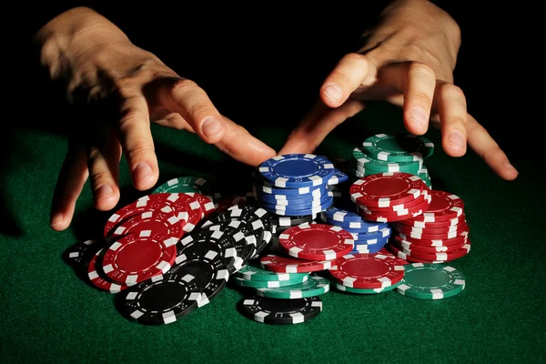 Fichas de póquer y las manos por encima de ella en la mesa verde —  Fotos de Stock