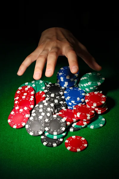 Poker chips and hand above it on green table — Stock Photo, Image