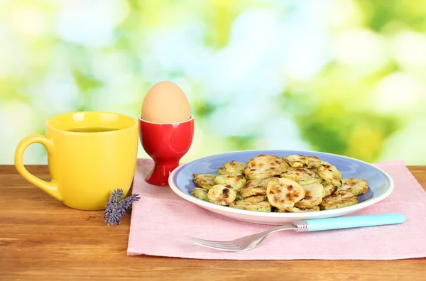 Stekt zucchini med ägg och kaffe till frukost på träbord på grön bakgrund — Stockfoto