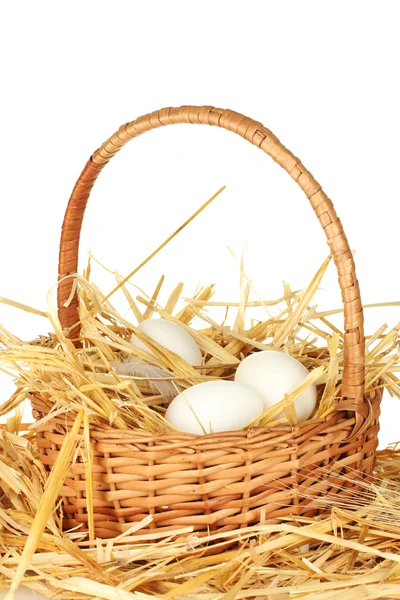 Białe jaja w wiklinowym koszu na słomce na białym tle — Zdjęcie stockowe