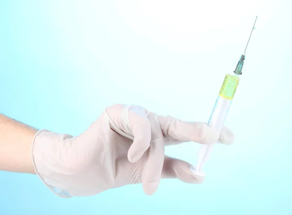 Syringe in hand on blue background Stock Image