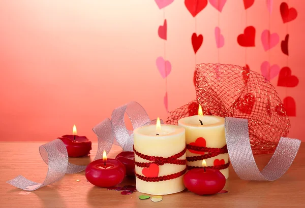 Candles for Valentine's Day on wooden table on red background Stock Photo