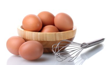 ahşap kase üzerinde beyaz izole kahverengi yumurta ve yumurta çırpma için metal çırpma teli