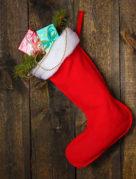 Weihnachtssocke mit Geschenken auf Holzgrund — Stockfoto