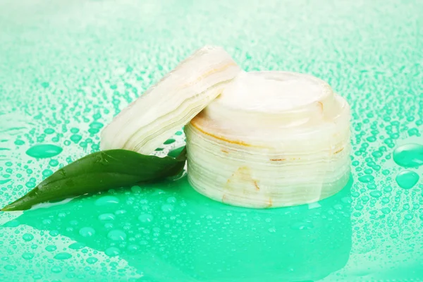 Nyitott üveg tejszín friss zöld leveles zöld háttér vízcseppek — Stock Fotó