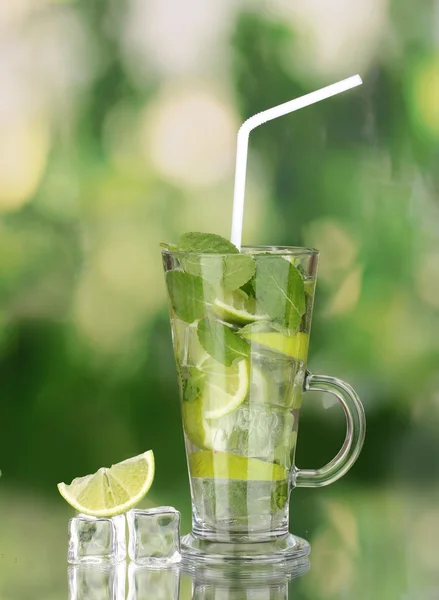 Verre de cocktail avec citron vert et menthe sur fond vert — Photo