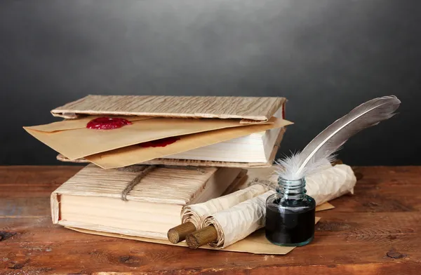 Old books, scrolls, feather pen and inkwell on wooden table on grey background — Stock Photo, Image