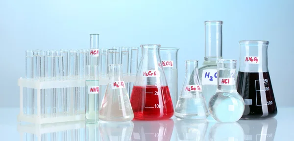 Тестовые трубки с различными кислотами на синем фоне — стоковое фото