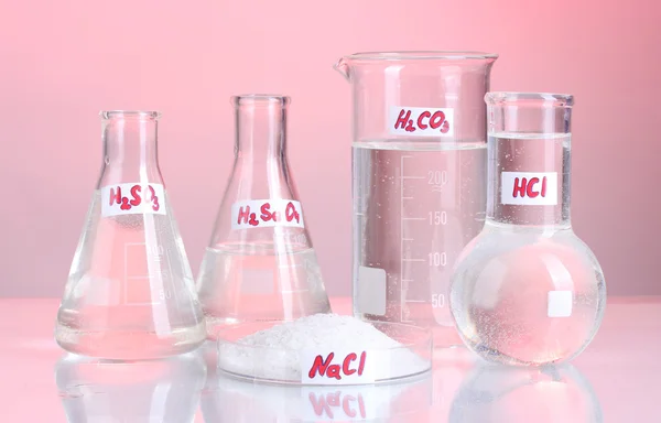 Tubos de ensaio com vários ácidos e produtos químicos sobre fundo rosa — Fotografia de Stock