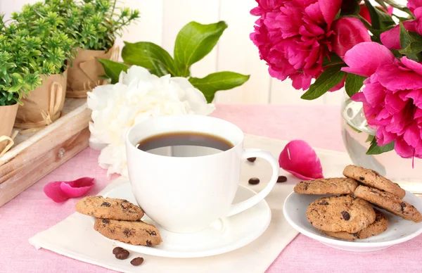 Taza de café, galletas y flores en la mesa en la cafetería —  Fotos de Stock