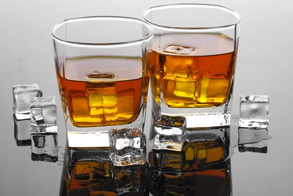 Dvě sklenice skotské whisky a ledu na šedém stole — Stock fotografie