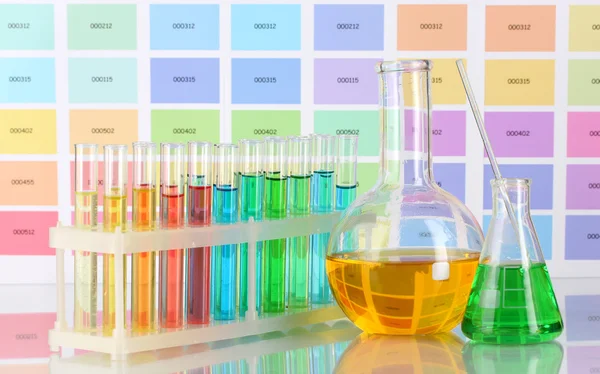 Tubos de ensayo y frascos con líquido de color sobre el fondo de muestras de color —  Fotos de Stock