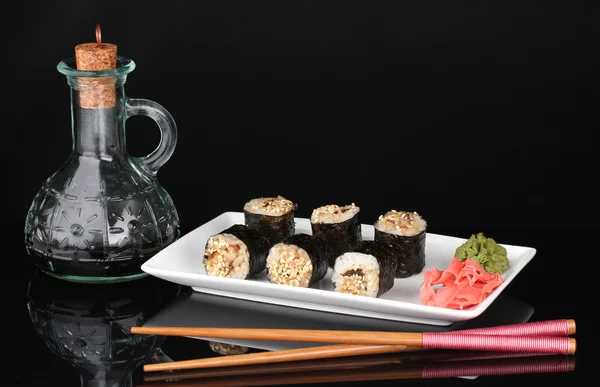 Tasty rolls served on white plate with chopsticks and soy sauce isolated on black — Stock Photo, Image