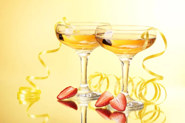 Glasses of champagne and strawberries on yellow background — Stock Photo, Image