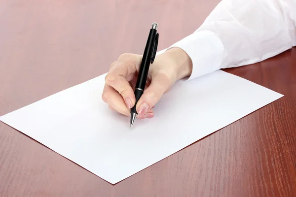 Mulher mão escrevendo no papel, na mesa de madeira — Fotografia de Stock