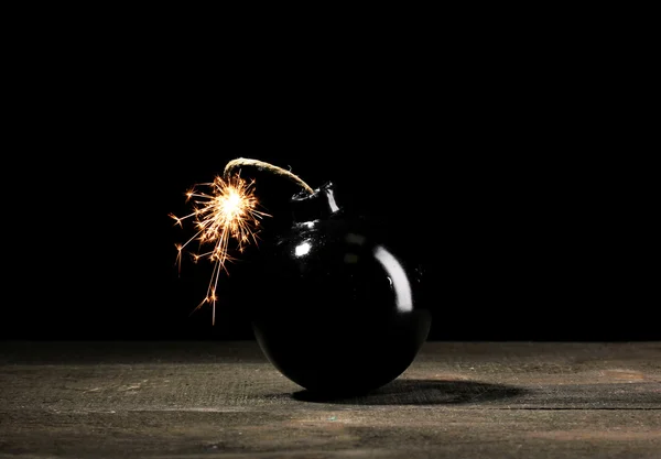 Bomba in stile cartone animato su tavolo di legno su sfondo nero — Foto Stock