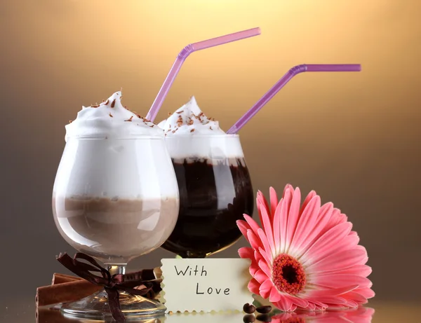 Glasses of coffee cocktail and gerbera flower on brown background