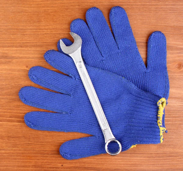 Wrench and gloves on wooden background — Stock Photo, Image