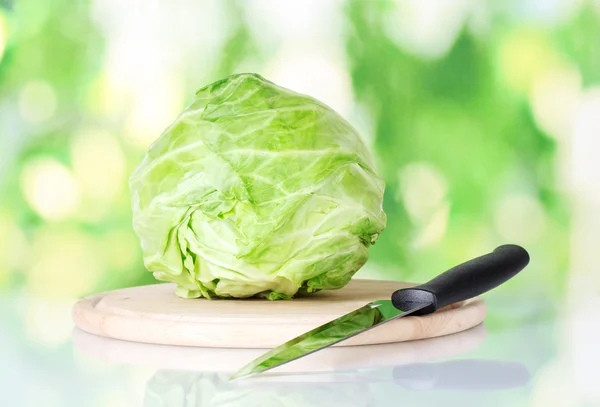 多彩的绿色背景上的刀在切菜板上白菜 — 图库照片