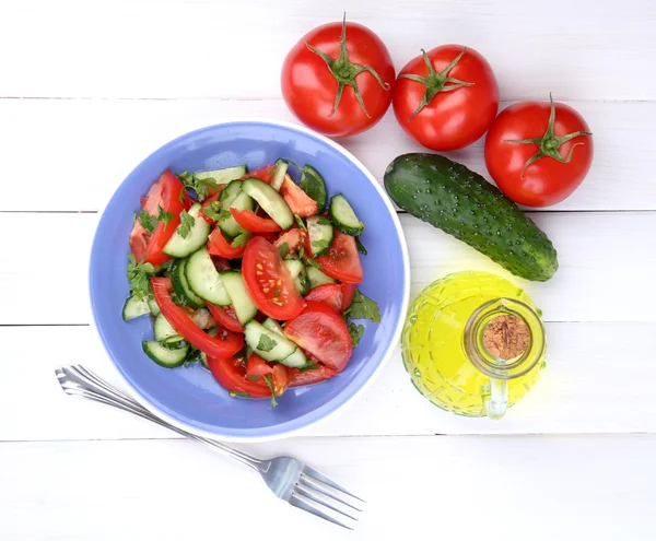 Frischer Salat mit Tomaten und Gurken auf weißem Holzgrund — Stockfoto