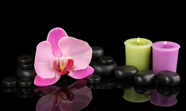 Spa stenen met orchideebloem en kaarsen geïsoleerd op zwart — Stockfoto