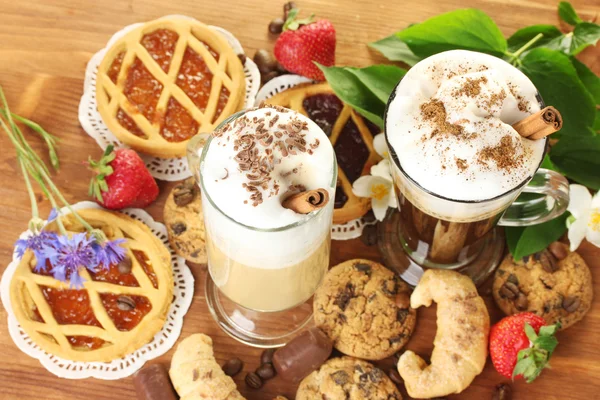 Copos de coquetel de café na mesa de madeira com doces e flores — Fotografia de Stock
