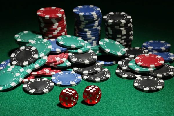 Kostky a žetony na poker na zeleném stole — Stock fotografie