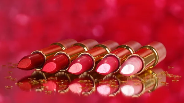 Hermosos lápices labiales sobre fondo rojo — Foto de Stock