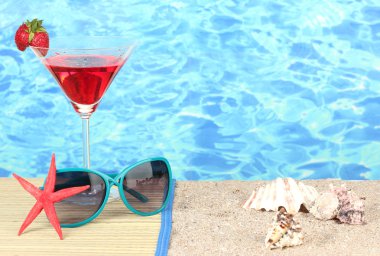 Beach composition of fashionable women's sunglasses and a refreshing drink clipart