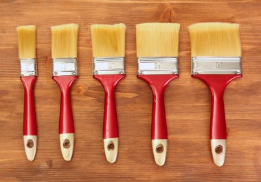 Paint brushes on wooden background clipart