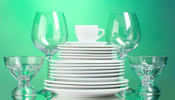 清洁盘子、 杯子和绿色背景上的眼镜 — 图库照片