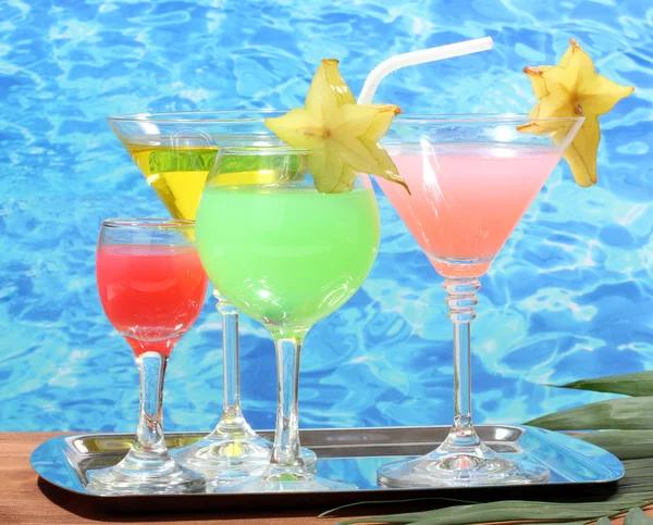 Glasses of cocktails on wooden table on blue sea background — Stock Photo, Image