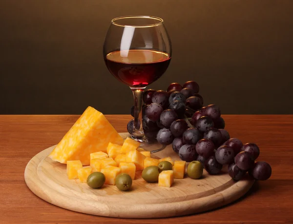 Viini viinilasissa ja juusto puupöydällä ruskealla pohjalla — kuvapankkivalokuva