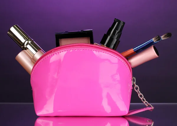 Bolsa de maquillaje con cosméticos y pinceles sobre fondo violeta — Foto de Stock