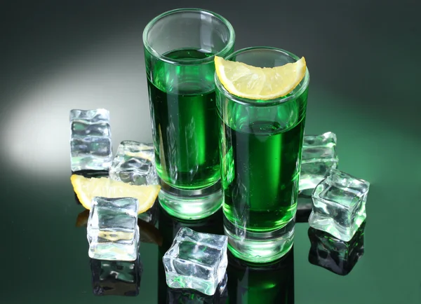 Zwei Gläser Absinth, Zitrone und Eis auf grünem Hintergrund — Stockfoto