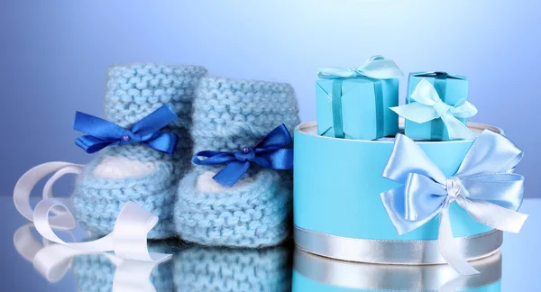 Piękne prezenty i trzewiki dziecka na niebieskim tle — Zdjęcie stockowe