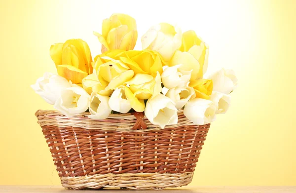 Vackra tulpaner i korg på träbord på gul bakgrund — Stockfoto