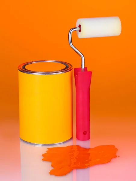 Lata de tinta com rolo de pintura sobre fundo laranja colorido — Fotografia de Stock