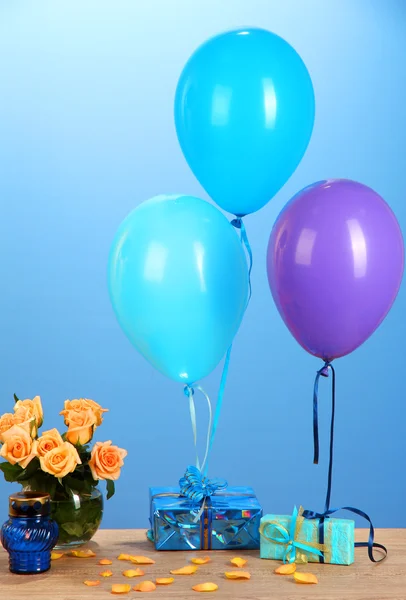 Romantisk present pojkvän. färgglada ballonger innehar en gåvor på blå bakgrund — Stockfoto