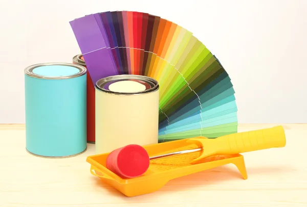 Latas de estanho com tinta, rolo, escovas e paleta brilhante de cores isoladas em branco — Fotografia de Stock