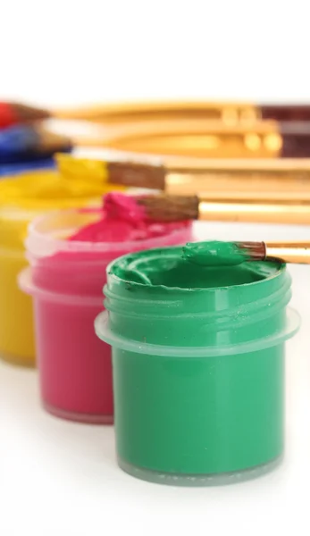 Brushes on the jars with colorful gouache on white background close-up — Stok fotoğraf