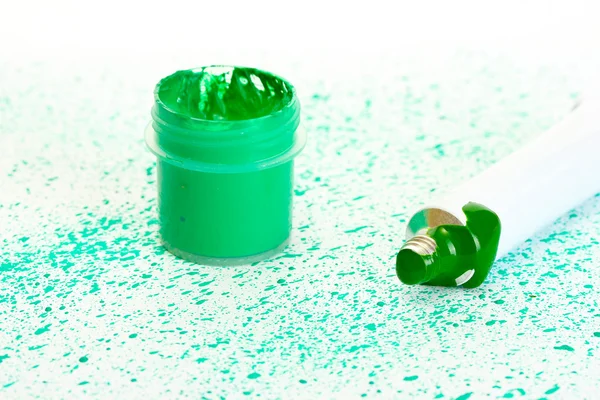 Pot met groene gouache en buis met groene waterverf op achtergrond van groene spray close-up — Stockfoto