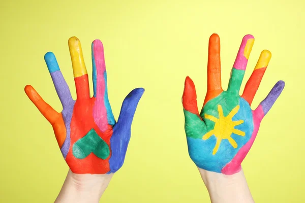 Brightly colored hands on green background close-up — Stock Photo, Image