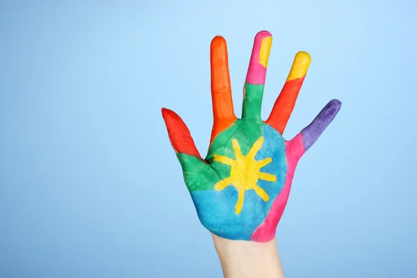 Brightly colored hand on blue background close-up — Stock Photo, Image